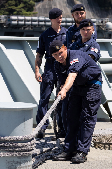 Seamen holding mooring rope on vessel