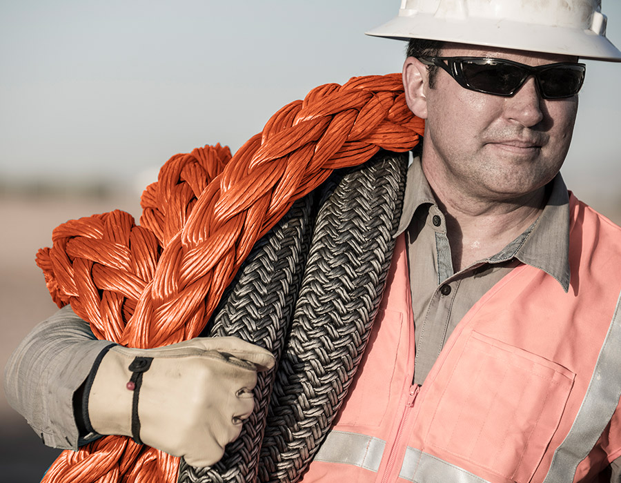 Worker carrying synthetic winch ropes by Samson Rope, used in mining and recovery operations